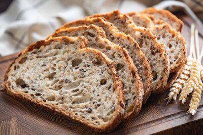 Sliced bread on a wooden board with wheat stalks, highlighting a delicious food display
